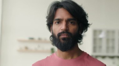 Kafasına yakın çekim yapan Arap müslüman adam mutfak odasında duruyor. Hintli etnik sakallı ciddi bir portre. Kameraya bakıyor. Sakin bir iş adamı.