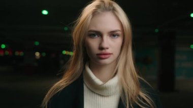 Portre gerçekten sakin, beyaz bir kadın, boş, karanlık bir park yerinde kameraya bakıyor. Kadın, milenyum bayan iş kadını, araba şoförü, müşteri müşterisi gece yarısı garajda.