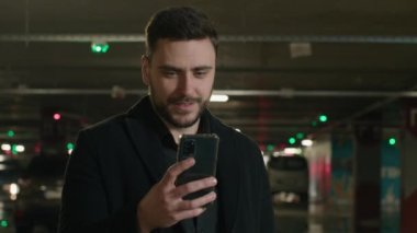 Beyaz iş adamı otoparkta duruyor. Cep telefonu sörfü yapıyor. Mesajlaşma taksisi yolluyor. Şehir şoförü, girişimci, müşteri müşterisi.