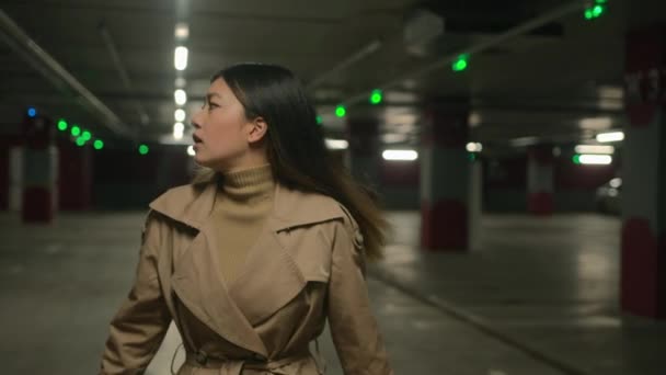 惊慌失措的亚洲女人独自走在地下害怕中国的日本女孩迷失在空旷的黑暗停车场回头看四周搜索帮助逃避危险的恐惧行动快点 — 图库视频影像