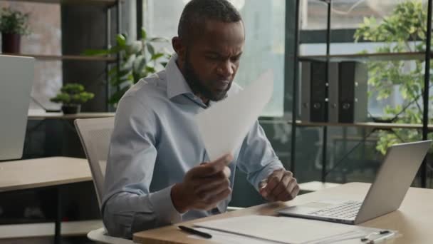 疲れ成熟した労働者アフリカ系アメリカ人の男性は 文書と仕事ノートパソコンは片頭痛の痛み疲れビジネスマンは 事務処理の目の緊張がオフィスで乾燥した目の過労をマッサージした後 目の緊張を感じます — ストック動画