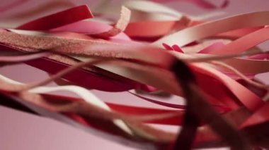Pembe arka planda sallanan beyaz ipek kurdeleli kırmızı. Moda işi sunumu. Yırtık bant kurdele katmanları, kumaş, saten kumaş, deri, çırpınan malzeme, üç boyutlu dijital animasyon.