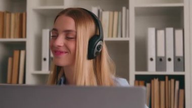 Mutlu, kaygısız, beyaz kadın öğrenci bürosu çalışanı işe ara veriyor. Kulaklıkla müzik dinliyor, dizüstü bilgisayarla dans ediyor, mikrofonda şarkı söylüyor, iş kadını dinliyormuş gibi yapıyor.