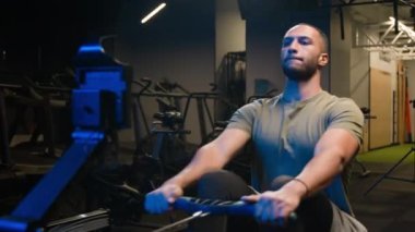 Afrikalı Amerikalı kaslı adam çok ırklı sporcu vücut geliştirici beden eğitimi spor antrenmanında spor aletleri pazısı trisepsleriyle oturarak geri çekilme egzersizi yapıyor.