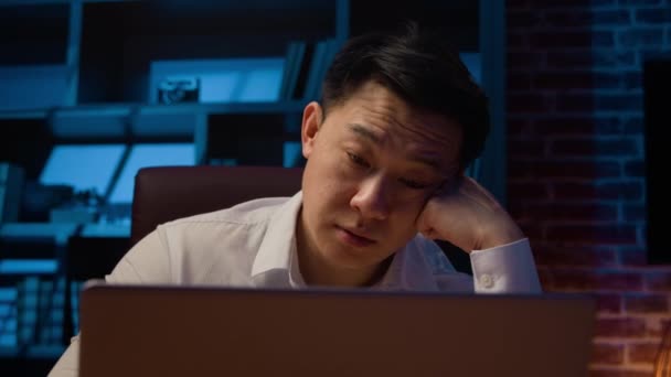 疲れたアジアの眠いビジネスマンの夜のオフィスワークでラップトップの締め切りで疲れ大人の韓国人男性マネージャー労働者眠気オンラインで働く深夜の低エネルギー眠って過労疲れ — ストック動画