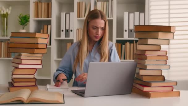 忙碌的白人女学生强调瘦小的女学生用笔记本电脑和书本做作业学习在线搜索信息知识问题准备大学图书馆的考试学习 — 图库视频影像