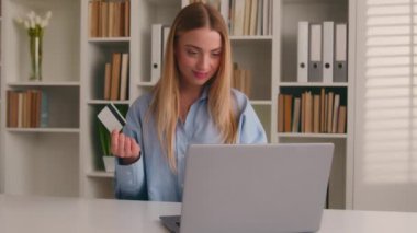 Ev ofisinden laptopuyla gülümseyen bir iş kadını internet üzerinden bilgisayar ve banka kredi kartı kızı müşterilerinin ecommerce uygulamasından satın alma siparişini öder.