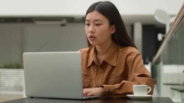 厌倦了的亚洲女商人坐在咖啡店里 在笔记本电脑上工作 悲痛欲绝 精疲力尽的中国女人 日本女人 懒惰的学生执行经理 厌倦了上网学习 精力超负荷 — 图库视频影像