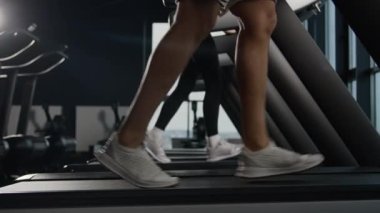 Spor salonunda koşu bandında koşu bandında koşan ayaklar atletizm koşucuları kadın ve erkek antrenman yapıyor spor ayakkabısı antrenmanı yapıyor sporcusu ve sporcu kadın kaslı bacakları spor kulübünde koşuyor.