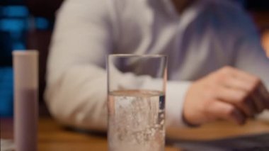 Asyalı hasta iş adamı hasta Koreli, gece çok çalışan iş adamı dizüstü bilgisayarlı iş projesiyle baş ağrısı migreni baş döndürücü ilaç atma baş döndürücü ilaç tabletini bir bardak su ağrısı kesiciye koy.