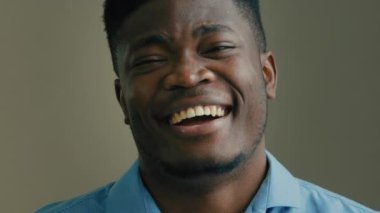 Kafadan vurulan mutlu Afrikalı Amerikalı çok ırklı adam gri arka planda heyecanlı iş adamı gülen samimi gülen, dişlek dişli gülümseme ofis şakasında eğleniyor şirket mizahında