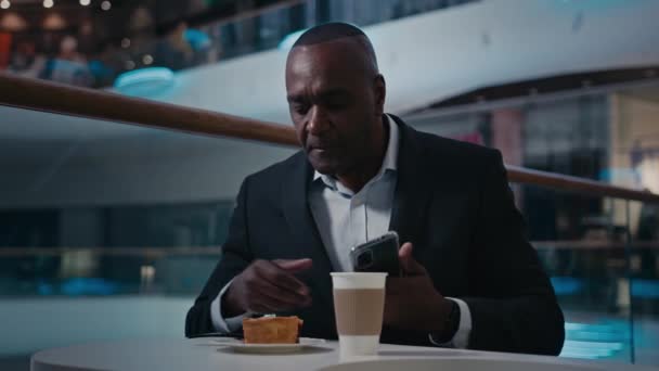 非洲裔美国中年商人咖啡桌成熟男子首席执行官与手机业务聊天放松吃蛋糕吃派喝茶喝咖啡休息与智能手机浏览 — 图库视频影像