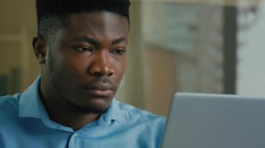 Afro-Amerikalı iş adamı profesyonel yönetici ev ofisteki erkek etnik yöneticiden dizüstü bilgisayarda çalışıyor internet odaklı iş adamı internette dijital verileri analiz ediyor.