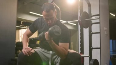 Çok ırklı erkek sporcu Afrikalı Amerikalı vücut geliştirme sporcusu spor salonunda spor eğitmeni. Spor salonunda kol egzersizi yapıyor. Halter kaldırıyor, ağırlık kaldırıyor, kas çalıştırıyor.