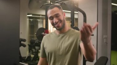 Gülümseyen Afrikalı Amerikalı erkek kişisel fitness antrenörü beden eğitimi sporcusu sporcu hoş geldin jest daveti, jest daveti, spor kulübü vücut geliştiricisinde çapraz kollar pozu.