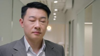 Portre Asyalı iş adamı ciddi orta yaşlı etnik erkek girişimci ofis şirketinde yetişkin bir şirket çalışanı koridorda kamera yöneticisi yöneticisi CEO avukat arıyor.