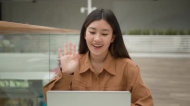 Asyalı kadın girişimci dizüstü bilgisayardaki video görüntüleme mesafesinde konuşuyor. Sanal webcam görüntülerini arıyor. Gülümseyen Koreli, etnik kökenli, Çinli bir iş kadını gibi konuşuyor.