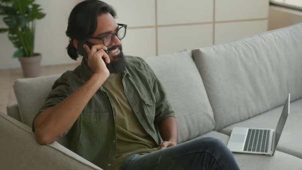 Muzułmanin Arabski Facet Freelancer Siedzieć Kanapie Laptopem Rozmawiać Telefon Komórkowy — Wideo stockowe