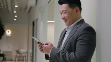 Asyalı yetişkin işadamı gülümsüyor cep telefonu internet üzerinden iş dünyası sosyal ağ mesajları akıllı telefon uygulaması kullanıyor internet sohbet orta yaşlı Koreli adam kurumsal ofis gülümsemesi