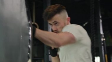 Profesyonel boksör erkek güçlü adam spor eldivenli boksör spor kulübünde boks torbası Kafkas sporcusu kickboksör aktif eğitiminde spor salonunda dövüş kutusunu yumrukladı.