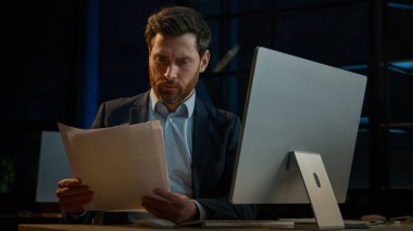 Busy Caucasian man lawyer work with documentation read business legal documents check financial paper contracts adult male businessman paying bank loan bills use online computer app in eveving office