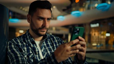 Kafkasyalı düşünceli İspanyol işadamı cep telefonu ekranına bakan ciddi bir adam akıllı telefon konuşmalarıyla mesaj yazıp alışveriş merkezinde ürün satın alan internet uygulaması.