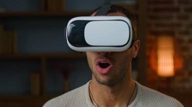 VR gözlüklü Afrikalı Latin erkek oyuncu oyun oynuyor. Sanal gerçeklik artırılmış gözlük kullanıyor. Gerçek simülasyon oyunları seyrediyor.