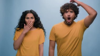 Çok ırklı çift şoke oldu İspanyol kadın erkek şaşkınlık mavi stüdyo arka planı şaşırttı kötü haber başarısızlık OMG reaksiyonu Aman Tanrım şaşırttı
