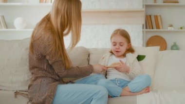 Kafkasyalı anne saç tokasıyla saç tokası yapıyor. Tarakla tarayıp evde oturan küçük çocukla konuşarak bebek kızına saç stili yapıyor. Çocuk bakımı rutinine hazırlanıyor.