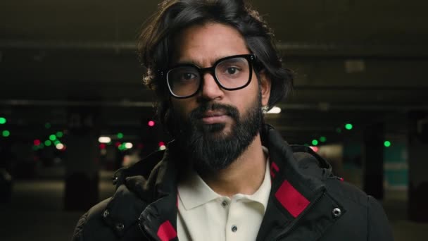 肖像画深刻なインドの男性ヒスパニック系ひげを生やしたアラビア語30眼鏡で千年のビジネスマン暗い地下の男のエンジニア工場労働者の駐車場でカメラを見てイスラム教徒のビジネスマン — ストック動画