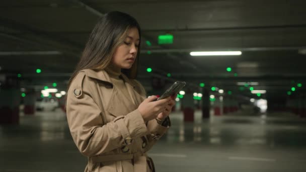 ビジネスウーマンアジア系中国人日本人女性クライアント韓国人女性顧客ドライバースタンド車の駐車場の利用携帯電話予約タクシー自動でスマートフォンアプリ検索インターネットで地下 — ストック動画