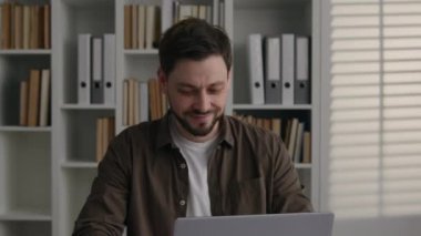 Hareket eden beyaz adam gülümseyen mutlu iş adamı ofis masasında dizüstü bilgisayarda çalışan ve üniversite kütüphanesinde internet üzerinden bilgisayar ağı e-öğrenimi yapan kişi.