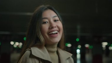 Mutlu Asyalı, etnik çeşitlilikte mutlu Koreli Çinli kadın Japon iş kadını portresi tatmin olmuş müşteri gülümseyen samimi gülüşler şehrin karanlık otoparkında eğlenceli, dişlek bir gülümseme
