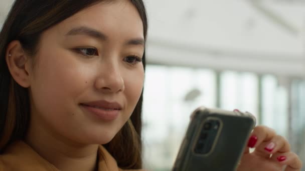 笑顔を閉じますアジアの日本の女性の肖像多人種の女の子のビジネス女性はソーシャルメディアのスマートフォンの画面を読みますオフィスで携帯電話を使用韓国の民族の女性の学生のチャットメッセージ — ストック動画