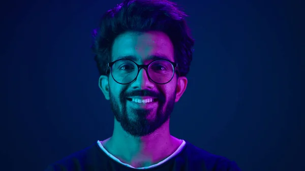 ポートレートインドの男イスラム教徒の男開発者コーディング労働者の笑顔コンピュータインターネット技術ハッカーアラビアの男性の眼鏡笑顔ネオンブルー紫外線スタジオの背景ハイテク将来のサイバー空間 — ストック写真