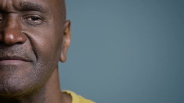 Kapalı çekimde yarı erkek, olgun Afro-Amerikalı kameraman görünümlü orta yaşlı hasta stüdyo gri arka plan görme sorunu görüşü lazer düzeltme göz doktorluğu sağlık hizmetleri