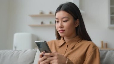 Asyalı Koreli iş kadını kadın serbest çalışan mutfakta çalışıyor. İyi haberler okuyor, gülümsüyor cep telefonu kullanıyor, internetten sipariş dağıtımı yapıyor, cep telefonu sohbeti yapıyor.