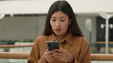 Gergin, sinirli, Asyalı, Asyalı, Koreli, Çinli, çok ırklı iş kadını, hoşnutsuz ofis müdürü, CEO, cep telefonu, telefon, arıza, iş sorunu.