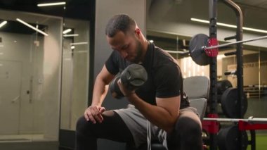 Spor salonunda biceps egzersizi yapan Afrikalı Amerikalı bir adam spor kulübünde güçlü vücut geliştirme sporu yapan güçlü bir sporcu ağır halter ağırlığı kaldıran ağırlık kaldırma antrenmanı yapan bir vücut geliştirme uzmanı.
