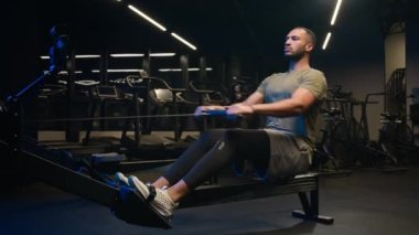 Güçlü atletik Afrikalı Amerikalı sporcu vücut geliştirme sporcusu erkek spor aletleriyle spor yapıyor. Spor kasları kasları, trisepsler, yatay çekme bloğunu geriye doğru itiyor.