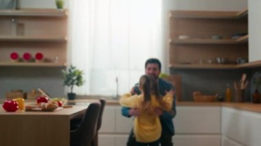 Mutfakta mutlu bir aile. Bulanık bir manzara. Küçük kız babasına koşuyor. Babasına koşuyor.