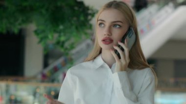 Alışveriş merkezindeki endişeli iş kadını kadın ofis çalışanı cep telefonuyla görüşmeler yapıyor. Sinirli Kafkasyalı kadın satış elemanı cep telefonu görüşmesi akıllı telefon ile iş sorununu çözer.