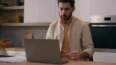 Kafkasyalı yorgun adam gözlerini ovuşturuyor gözlük takıyor gözlük takıyor uzaktan bilgisayarla çalışıyor mutfak işçisi erkek bilgisayar işi internet ödemesi yapıyor.