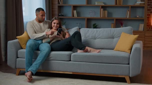 Diverse Man Woman Interracial Couple Homeowners Relax Sofa Talk Video — Stock Video