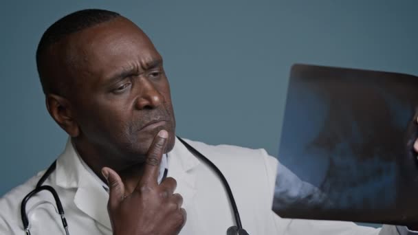 Dojrzałe Zamyślony Afrykański Lekarz Amerykański Mężczyzna Badania Rentgenowskie Niebieskim Tle — Wideo stockowe
