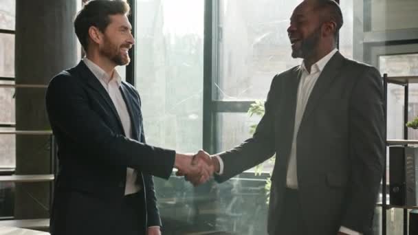 白人男性求職者インタビューアフリカのHr雇用主との正式な握手二つの多様な人種のビジネスマンが笑顔で話して成功したビジネスミーティングを握手取引パートナーシップを作る — ストック動画