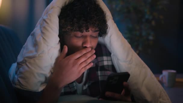 震惊的印度男子阿拉伯男子惊奇地在电话社交媒体上看到消息 惊讶地发现深夜在沙发上穿着毛毯躺在沙发上 毛绒绒的小玩意上瘾了 — 图库视频影像