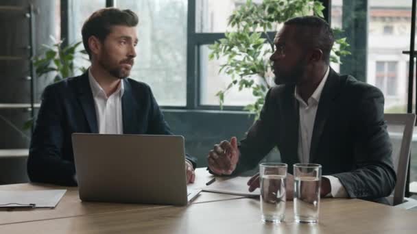 2人の多様なビジネス同僚多人種間のビジネスマン白人とアフリカ系アメリカ人男性の労働者起業家マネージャー深刻なチェック書類書類書類プロジェクトノートパソコンの問題について議論する — ストック動画