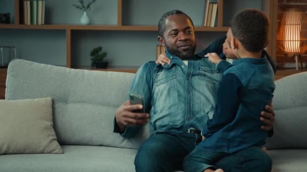 Afroamerikansk Far Med Mobiltelefon Hemma Soffa Prata Med Två Pojkar — Stockvideo