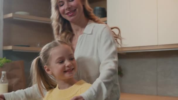 幸せな家族でキッチンで白人可愛いです小さな子供の娘抱擁とともに手で持っていますお母さんダンスと一緒に楽しみを持っていますダンス抱っこ朝食ボンディング愛情 — ストック動画